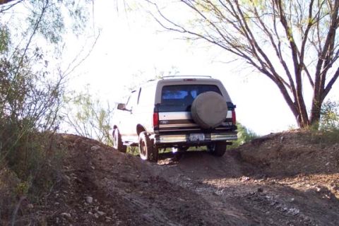 1996 Ford Bronco - This 1996 Ford Bronco navigates a steep dirt incline, its rear profile and external spare tire.