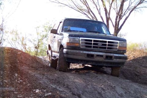 1996 Ford Bronco - This Ford Bronco is navigating a challenging off-road terrain with muddy slopes.