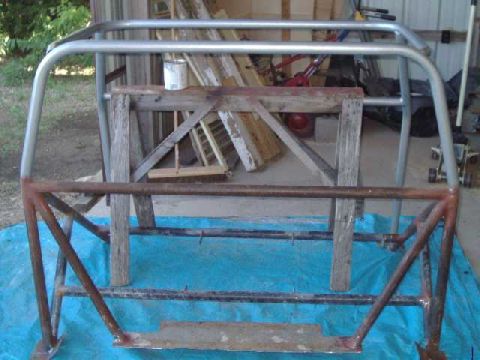 1984 Ford Bronco - A metal roll cage assembly is shown, resting on a blue tarp and supported by wooden beams.