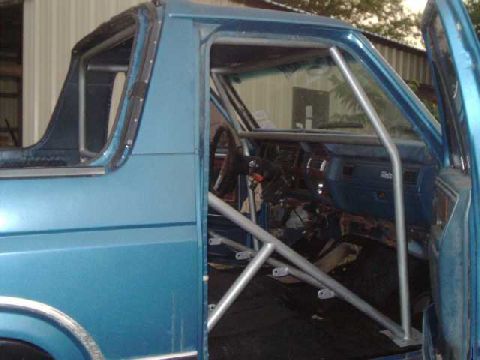1984 Ford Bronco - Interior view of a blue 1984 Ford Bronco a roll cage and racing seat.