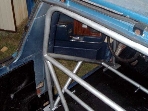 1984 Ford Bronco - A custom roll cage is installed inside the vehicle, with a view of the door panel and interior.
