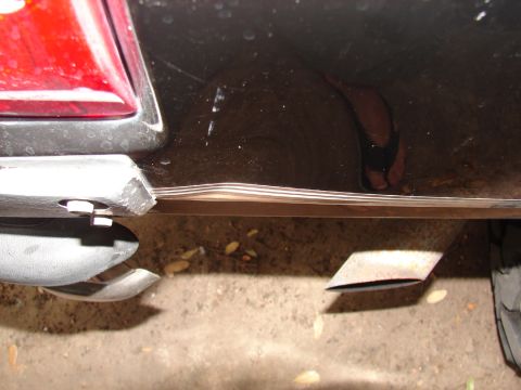 1996 Ford Bronco - This photo shows the rear bumper and exhaust system of a vehicle, with a reflection of footwear visible.