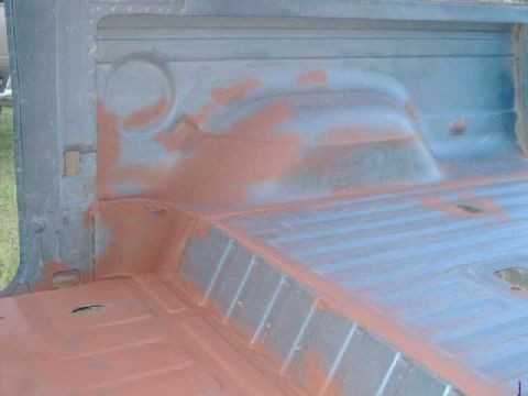 1984 Ford Bronco - Truck bed interior showing primer application on the floor and wheel wells.