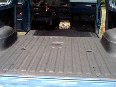 1984 Ford Bronco - The interior and bed of a blue Ford Bronco are visible, with the dashboard and cargo area showing.