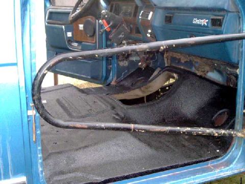 1984 Ford Bronco - Interior view of a blue vehicle, showing a roll cage and worn interior components.