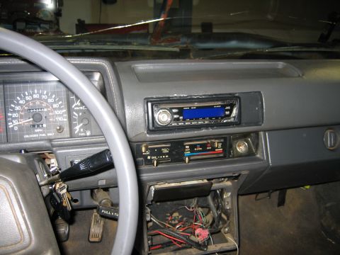1986 Ford F-150 - The interior of a 1986 Ford F-150 shows a cracked windshield, aftermarket radio, and exposed wiring under the dash.