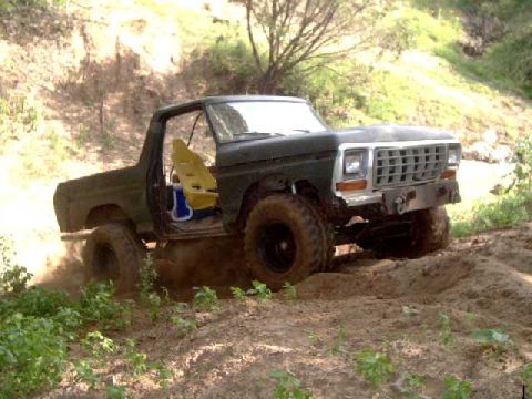 1984 Ford Bronco - This dark green Ford Bronco is navigating a dirt trail, kicking up dust as it goes.