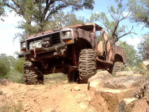 1984 Ford Bronco - This heavily modified Ford Bronco navigates a challenging rocky trail, its off-road capabilities.