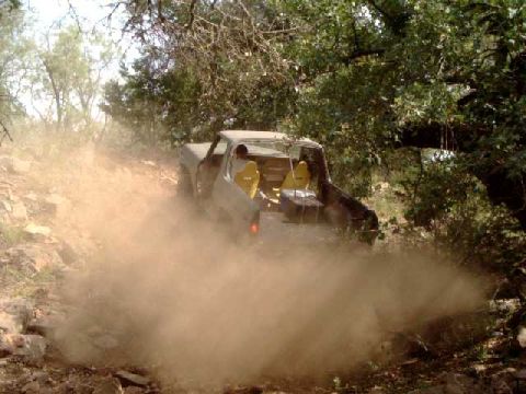 1984 Ford Bronco - This 1984 Ford Bronco is navigating a dusty, rocky trail with trees overhead.