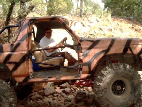 1984 Ford Bronco - A man drives a camouflaged Ford Bronco off-road.