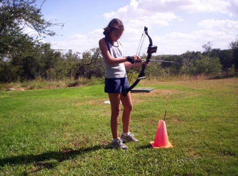 1986 Ford Bronco - A young girl practices archery outdoors, focusing on her shot with a compound bow.