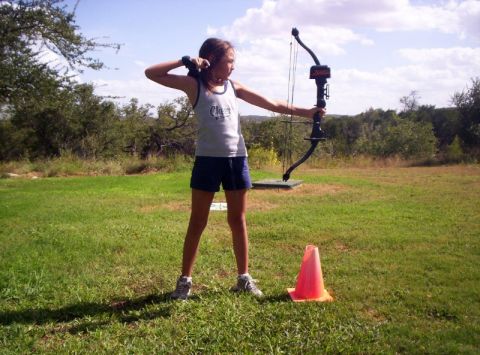 1986 Ford Bronco - A young girl practices archery outdoors, drawing back her bow with focus.