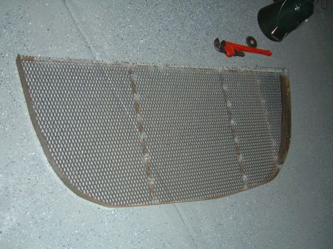 1993 Ford Bronco - A metal grille, likely a vehicle part, lies on a garage floor with tools nearby.
