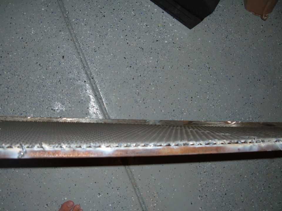 Close-up of a vehicle radiator with a speckled garage floor in the background