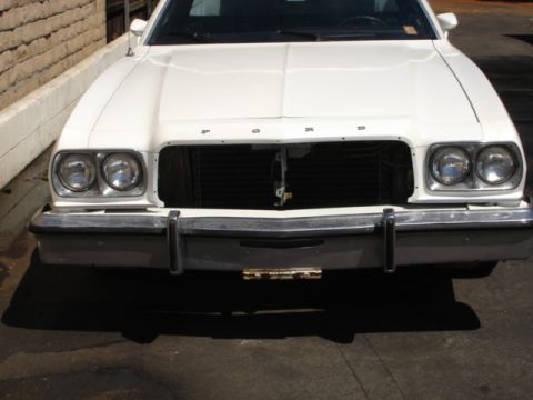 1973 Ford Ranchero - Front view of a white Ford Ranchero, missing its grille, with a chrome bumper and dual headlights visible.