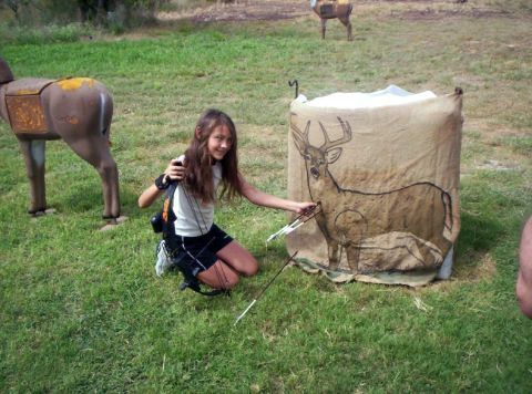 1986 Ford Bronco - A young girl practices archery, aiming her bow and arrow at a target depicting a deer.