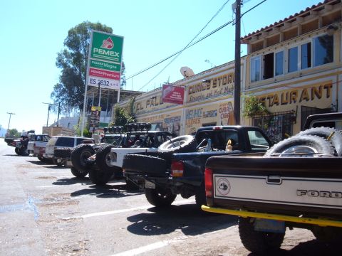 1985 Ford Ranger - Several off-road pickup trucks are parked in a row outside a store and restaurant.