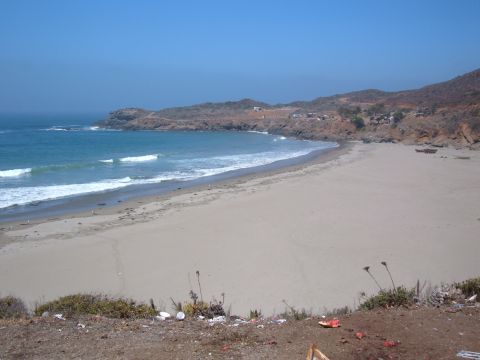 1985 Ford Ranger - Coastal landscape with a sandy beach, blue ocean, and hills in the background.