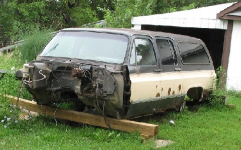 1995 Ford Bronco - This abandoned SUV sits on wooden beams with its front end dismantled, revealing the engine bay and wiring.