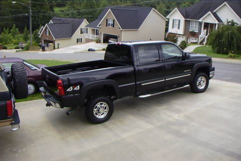 1995 Ford Bronco - Black pickup truck with 4x4 badging parked in a suburban driveway.
