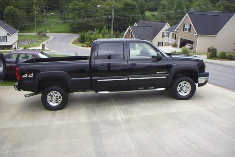 1995 Ford Bronco - A black pickup truck with a crew cab and four-wheel drive is parked in a suburban driveway.