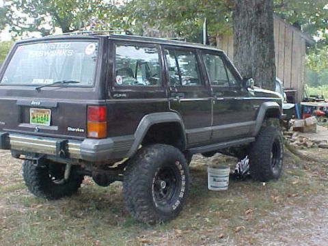 1968 Ford Mustang - This Jeep Cherokee is modified with large off-road tires and appears to be parked in a rural setting.