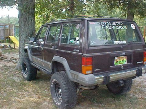 1968 Ford Mustang - A Jeep Cherokee XJ is parked outdoors, aftermarket wheels and stickers on its rear window.
