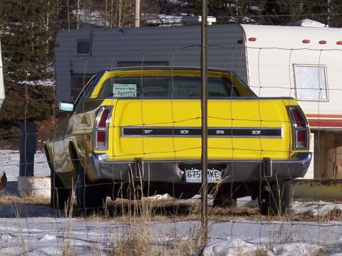 1972 Ford Ranchero - Rear view of a yellow 1972 Ford Ranchero pickup truck parked behind a fence.