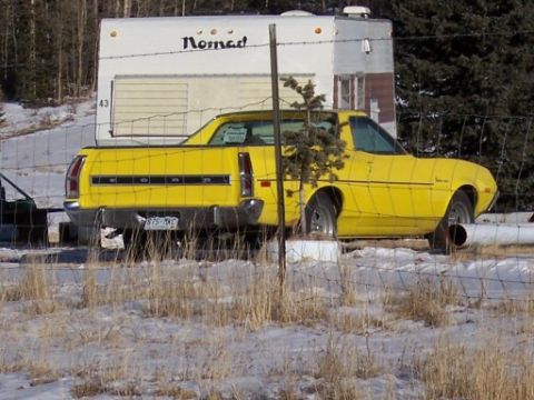 1972 Ford Ranchero - A yellow 1972 Ford Ranchero is parked in front of a Nomad trailer during winter.