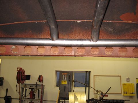 1977 Ford F-150 - Close-up view of a vehicle's undercarriage, showing custom roll cage and structural supports in a workshop setting.