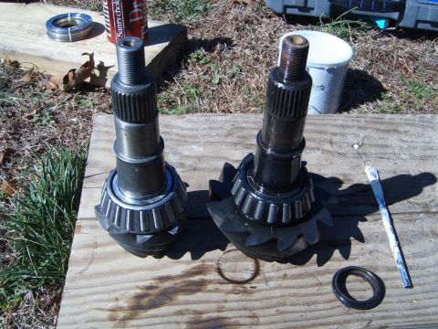 1988 Ford Bronco - Two differential gears and a bearing kit are laid out on a wooden surface, with a can of soda and other tools nearby.