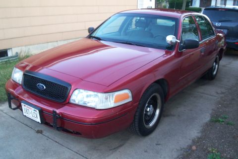 2001 Ford Crown Victoria - A red Ford Crown Victoria is parked in a driveway next to a dark SUV.