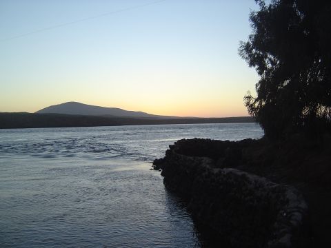 1985 Ford Ranger - Sunset over a river with mountains in the distance and a rocky shoreline.