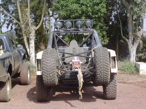1985 Ford Ranger - Two off-road vehicles are parked side-by-side on a dirt surface with trees in the background.
