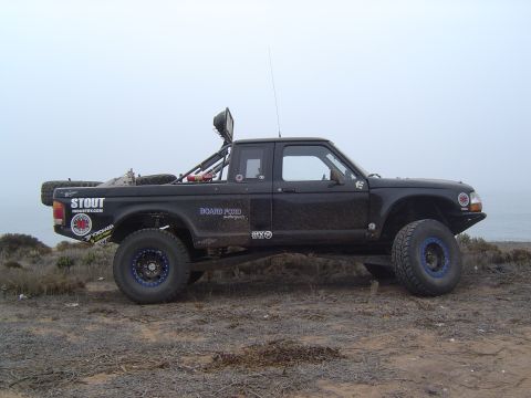 1985 Ford Ranger - Modified black pickup truck with off-road tires and a roll cage is seen from the side.