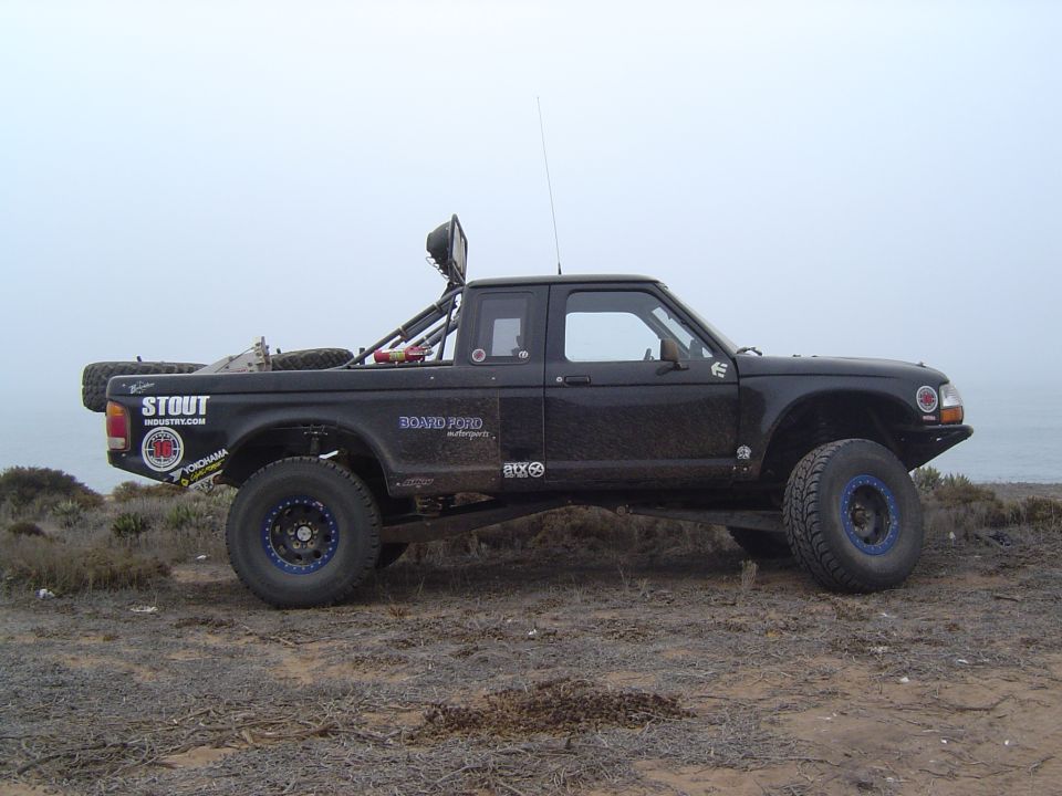 Black Ford Ranger prerunner off-road truck, side view on foggy coast