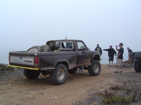 1985 Ford Ranger - A brown Ford Ranger pickup truck is parked on a cliff overlooking the ocean, with spare tires loaded in the bed.