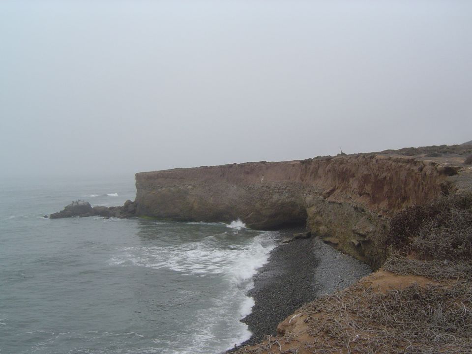 ocean waves crashing on a rocky shore with a cliff overhead