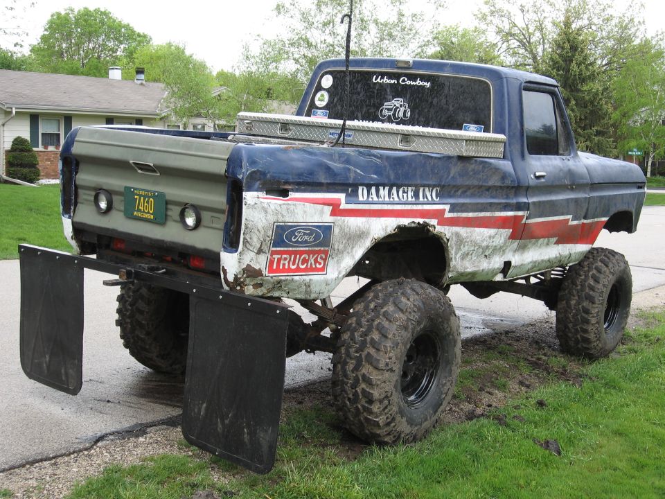 Rear view of a lifted 1977 Ford F-150 with large tires and mud flaps