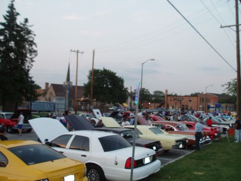 2003 Ford Crown Victoria - A gathering of vehicles at an outdoor event, with several cars on display and people milling around.