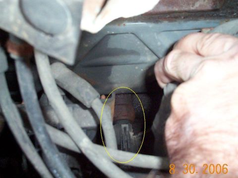 1989 Ford F-150 - A hand is shown reaching into the engine bay, interacting with the wiring harness.