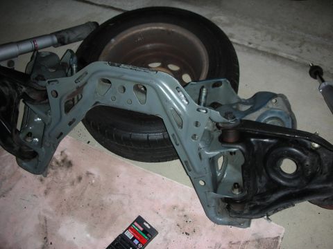 1990 Ford Mustang - Car suspension components and a spare tire are laid out on the floor.