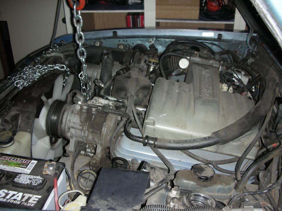 Dusty Ford Mustang engine bay with lift chain and Interstate battery