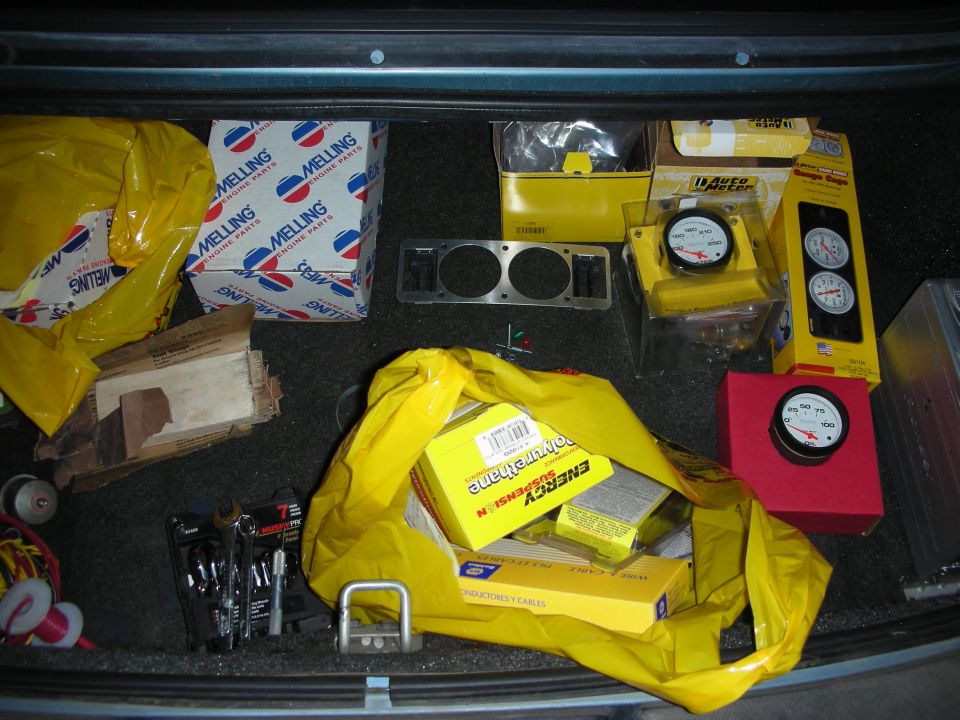 New Auto Meter gauges, Melling engine parts, and Energy Suspension boxes laid out in a trunk
