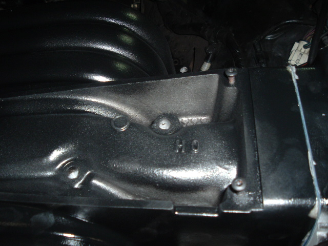 Close-up of a black plastic intake manifold and cover inside a dim engine bay