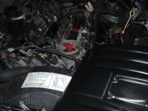 1989 Ford LTD Crown Victoria - Dimly lit engine bay with a black-painted intake/air cleaner assembly in the foreground carrying an emissions specification decal, surround…
