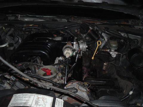 1989 Ford LTD Crown Victoria - Engine bay of a V8 with the black upper intake manifold, throttle body, yellow oil dipstick handle and brake master cylinder reservoir visi…