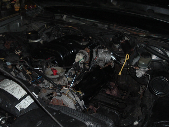 Engine bay work in progress with black intake, bare throttle body, and disconnected wiring