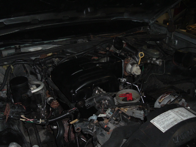 Dark engine bay work-in-progress with black composite intake manifold and disconnected wiring harness connectors