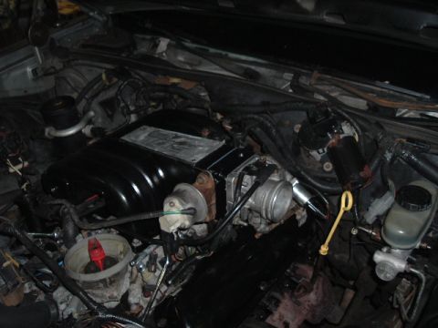 1989 Ford LTD Crown Victoria - Engine bay view of a V8 with a black plastic intake manifold, throttle body, and yellow transmission dipstick handle visible; brake master…